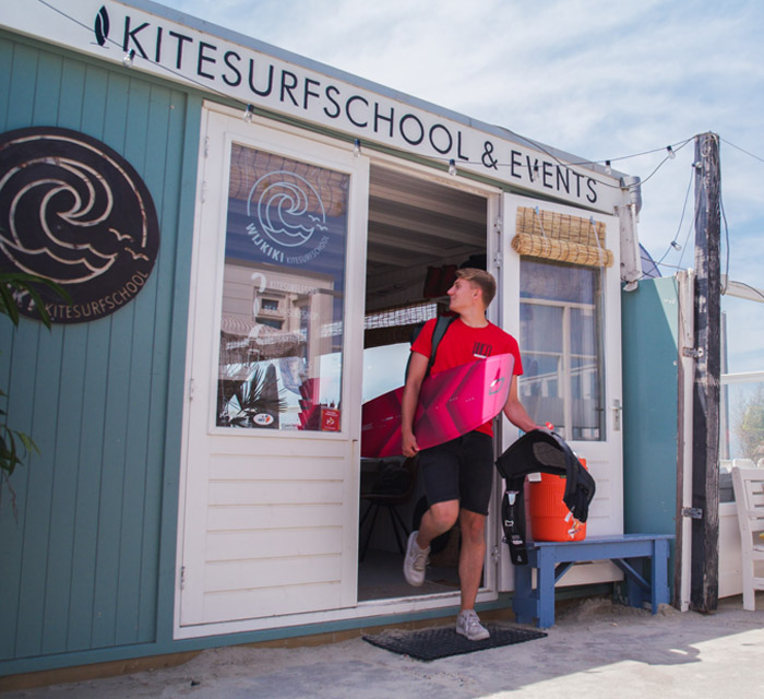 jongen loopt uit strandtent met surfboard